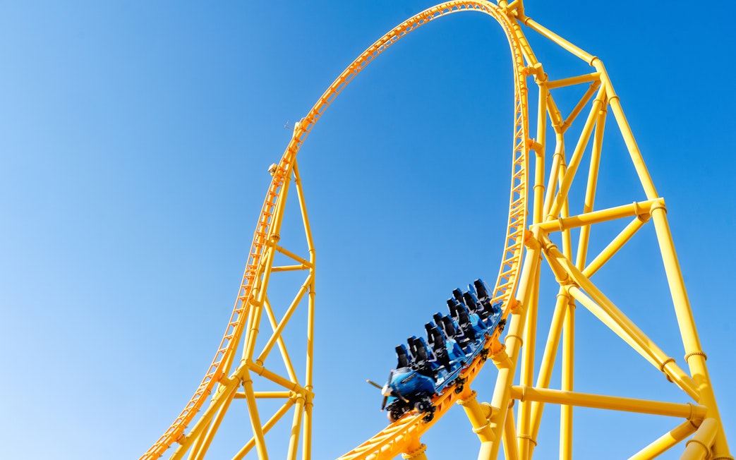 Roller coaster loop at Six Flags Qiddiya City against blue sky.