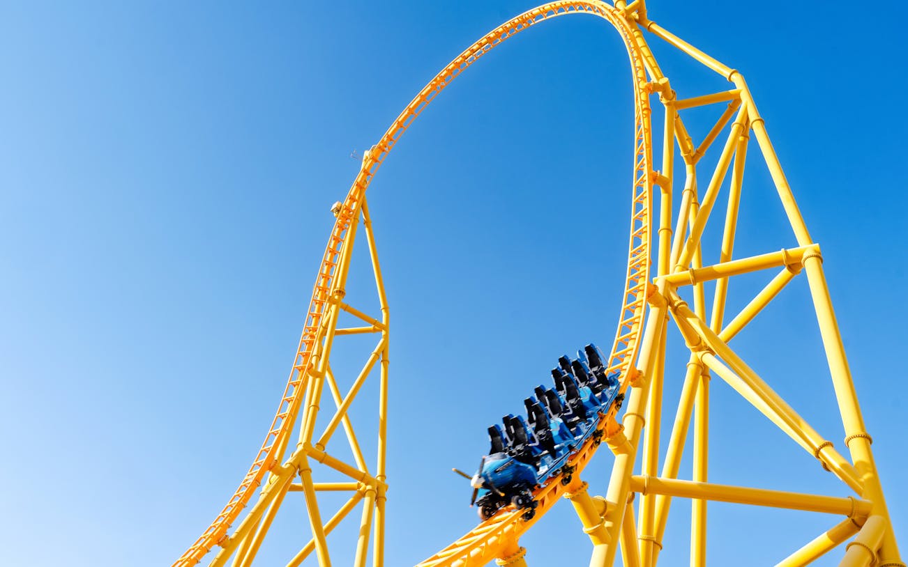Roller coaster loop at Six Flags Qiddiya City against blue sky.
