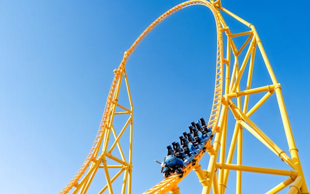 Roller coaster loop at Six Flags Qiddiya City against blue sky.