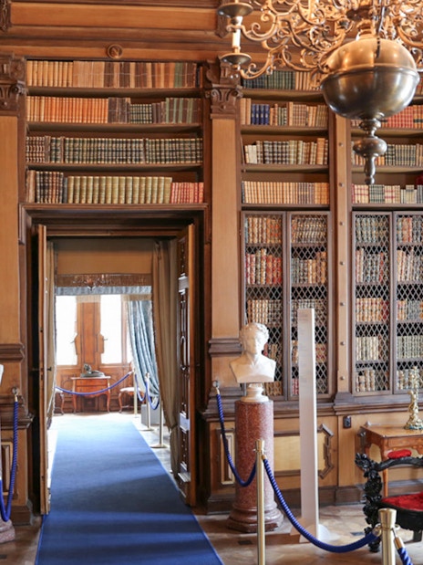 Miramare Castle reading room with bookshelves, busts, and a globe.