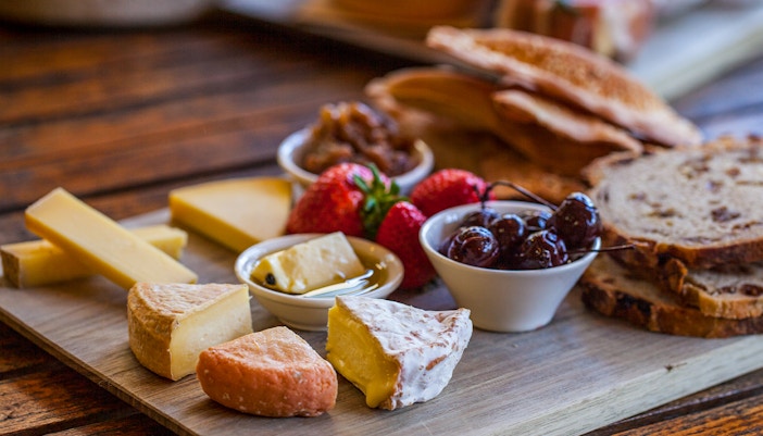 Tour group savoring gourmet food with Bruny Island coastline in the background.