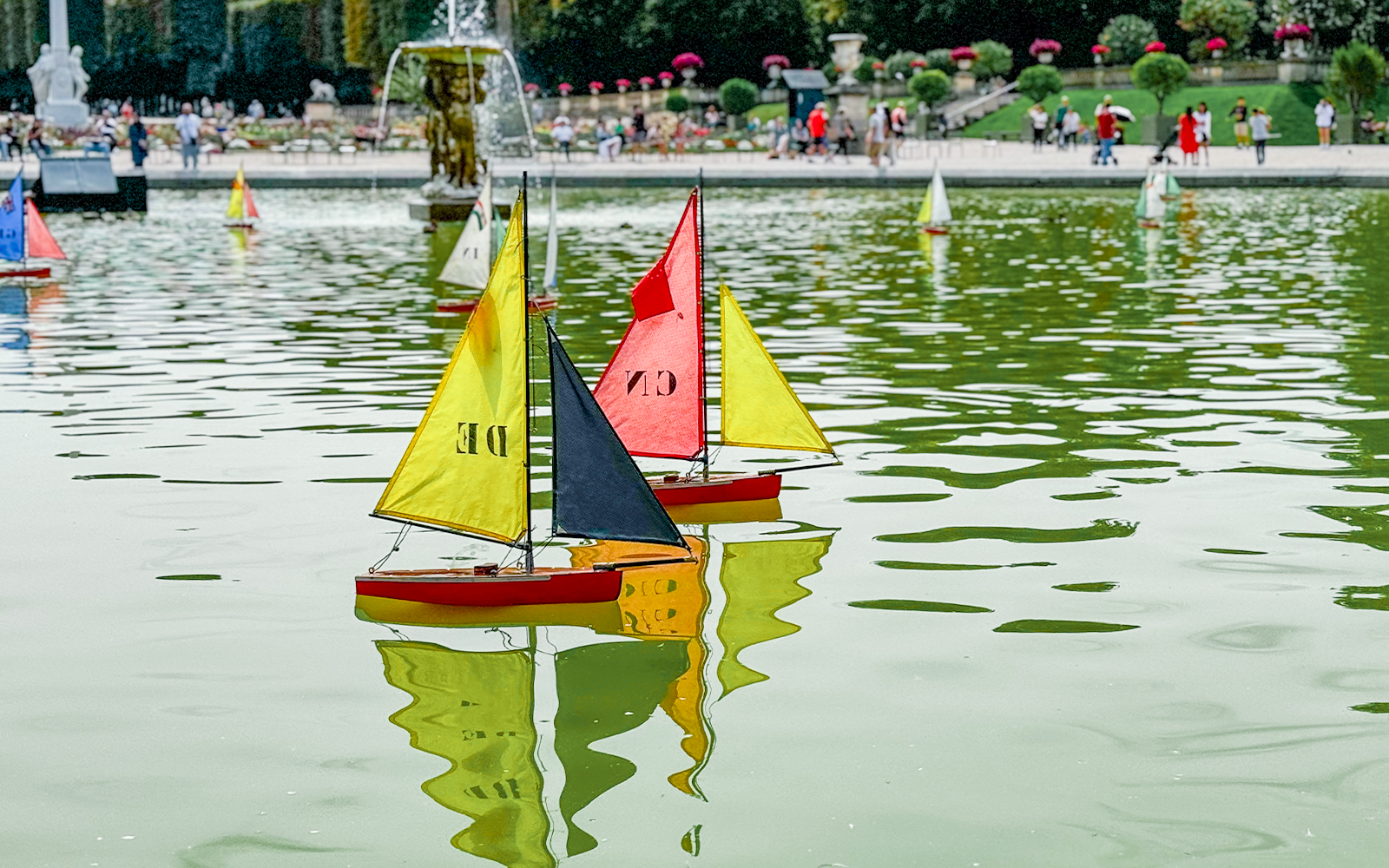 Children sailing toy boats in the pond at Tuileries Garden, Paris.