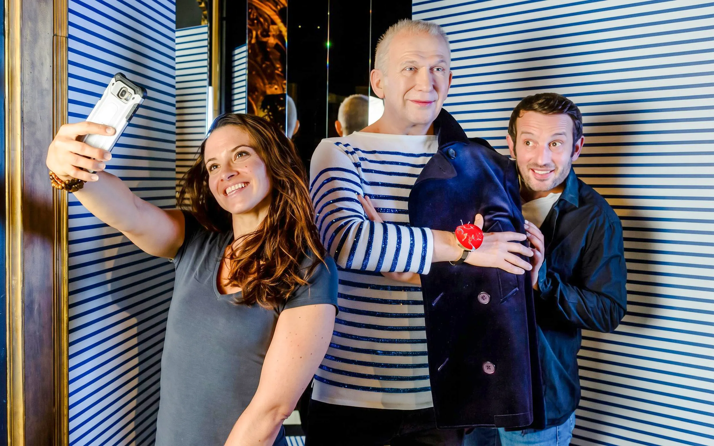 Visitors taking a selfie with a wax figure at Grévin Wax Museum, Paris.