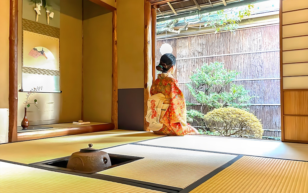 Person in kimono sitting in traditional Kyoto tea room, looking at garden.