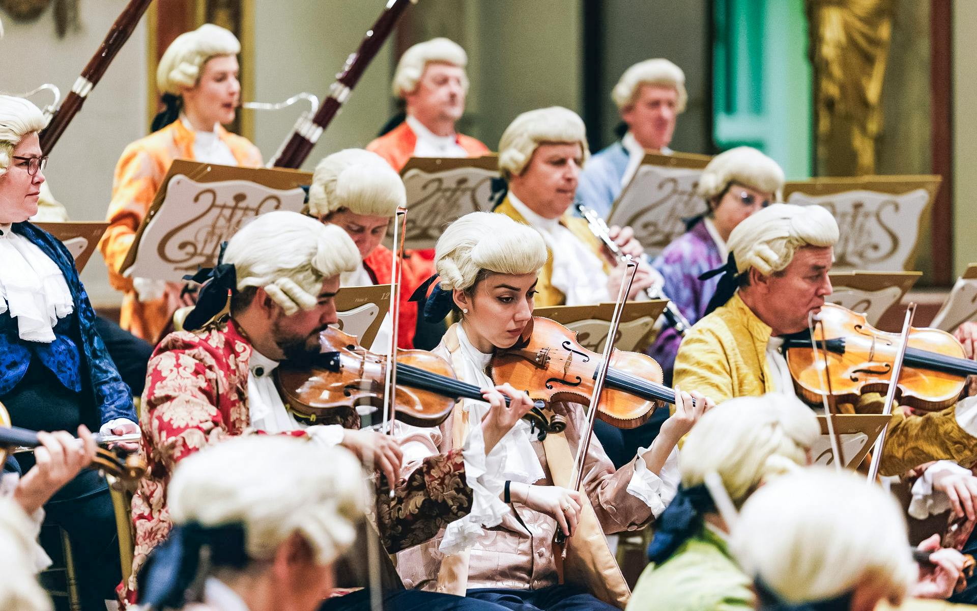 Musicians in period costumes performing at a Mozart orchestra concert.