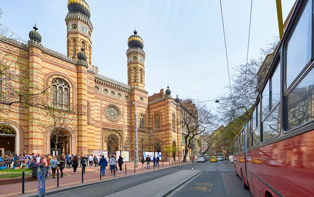 Central Synagogue of Budapest with visitors and a tram passing by.