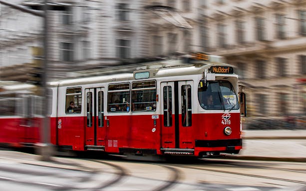 Red tram moving through a city street in Austria.