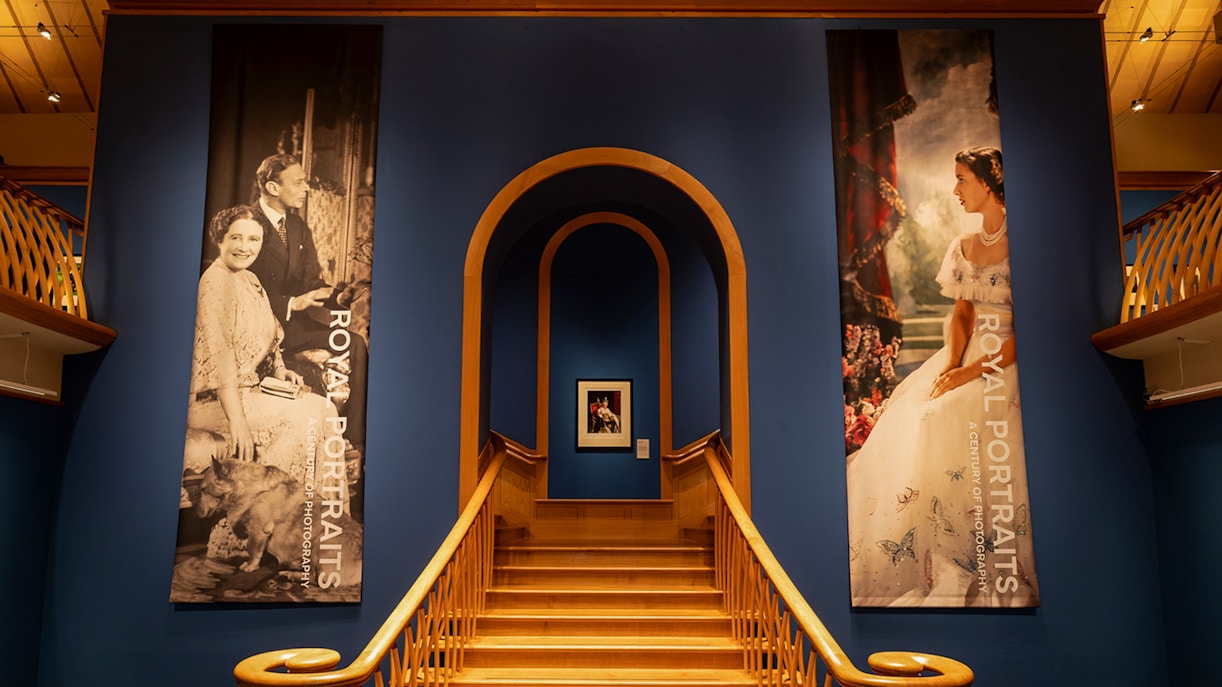 Staircase leading to The King's Gallery at the Palace of Holyroodhouse, featuring royal portraits.