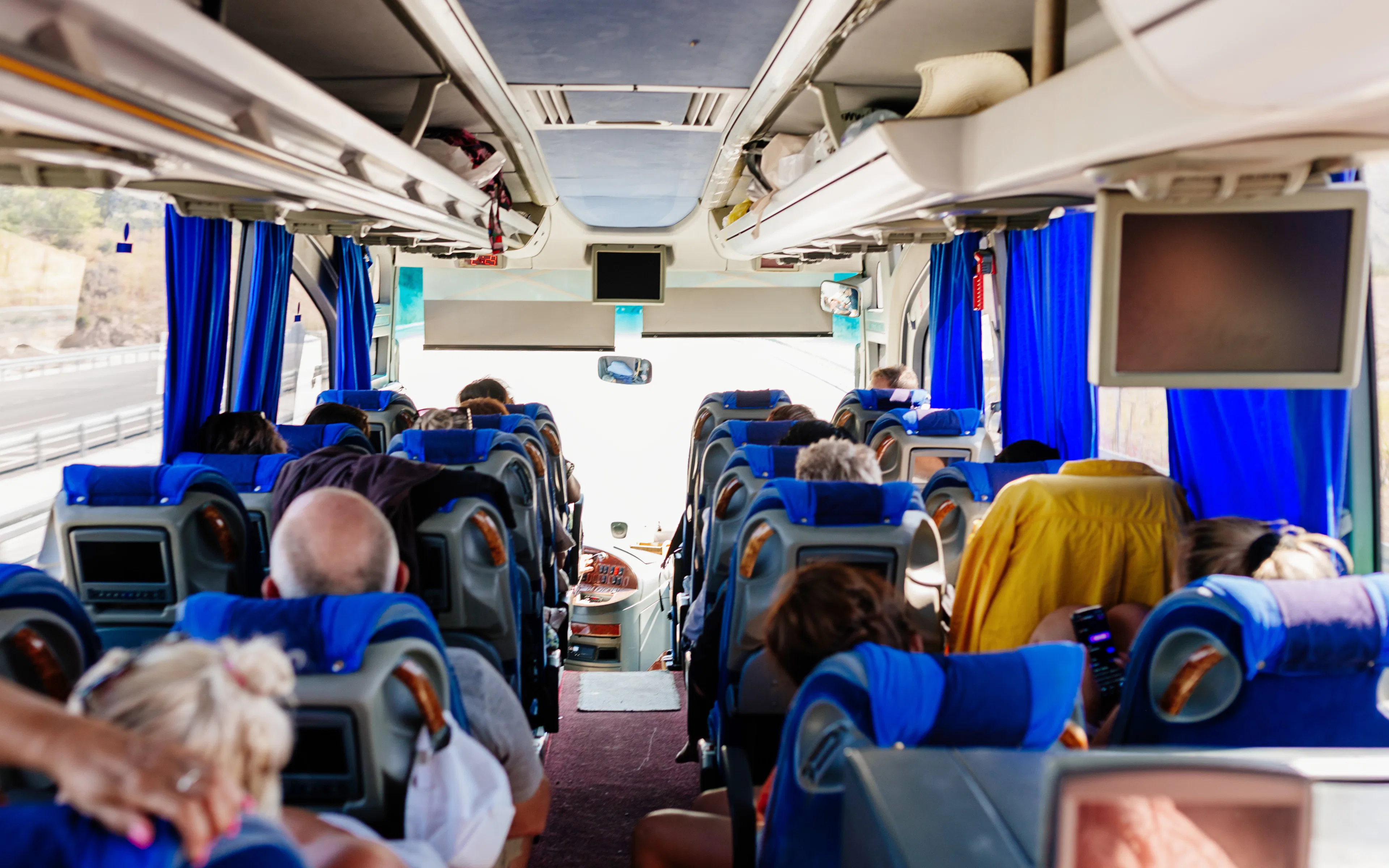 Passengers seated inside an air-conditioned tour bus.