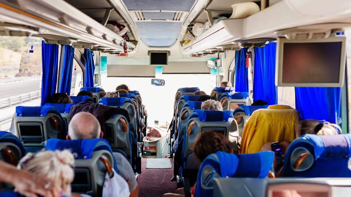 Passengers seated inside an air-conditioned tour bus.