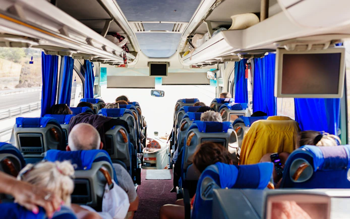 Passengers seated inside an air-conditioned tour bus.