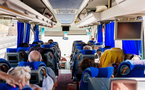 Passengers seated inside an air-conditioned tour bus.