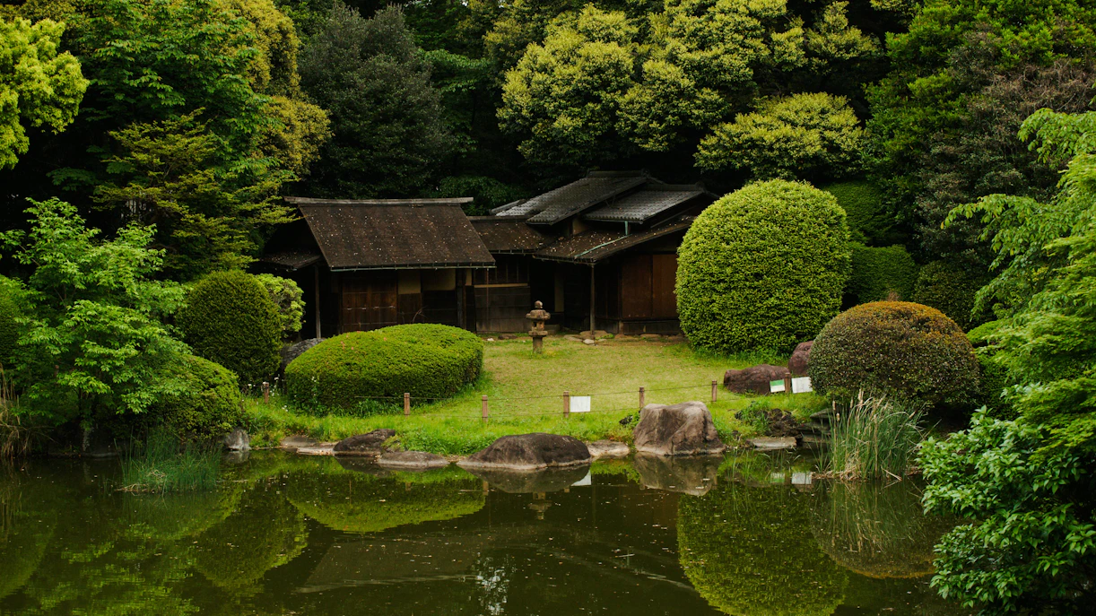 Japanese garden with traditional wooden structures behind Tokyo National Museum in Ueno Park.