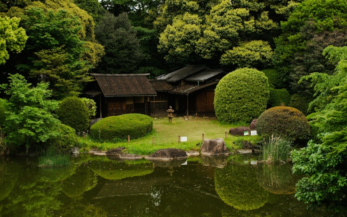 Japanese garden with traditional wooden structures behind Tokyo National Museum in Ueno Park.