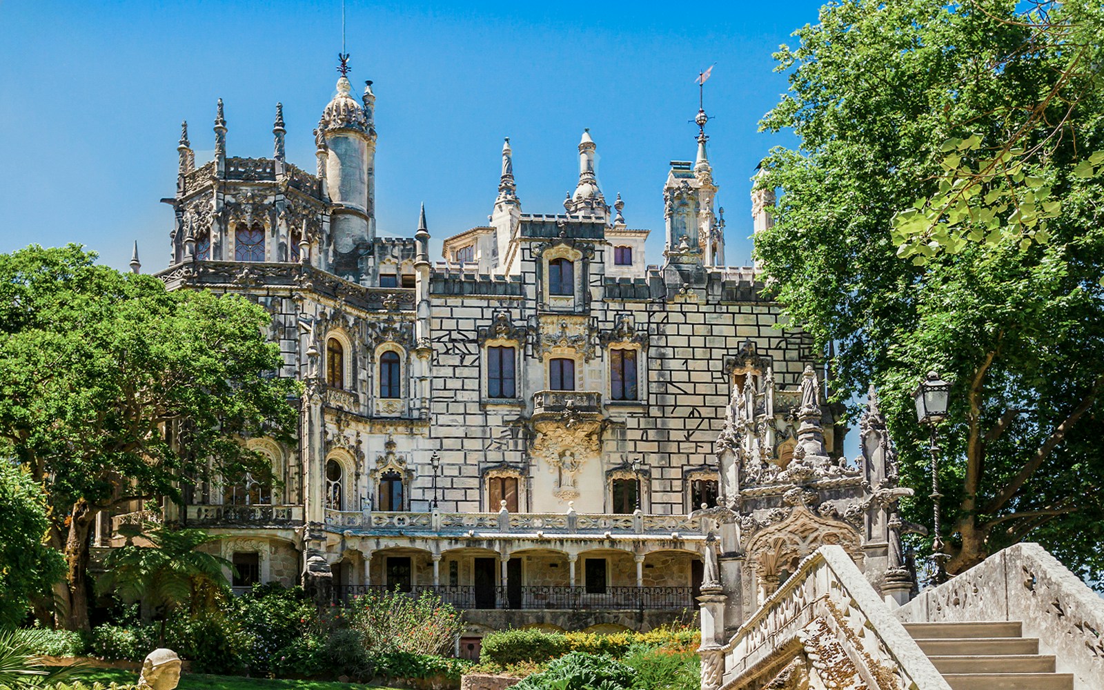 Quinta da Regaleira palace facade with ornate architecture and lush greenery in Sintra, Portugal.