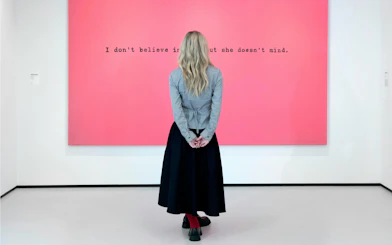 Visitor viewing pink artwork with text at Moco Museum, London.