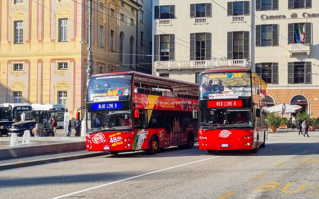 Hop-on hop-off tour buses in Genoa city center.