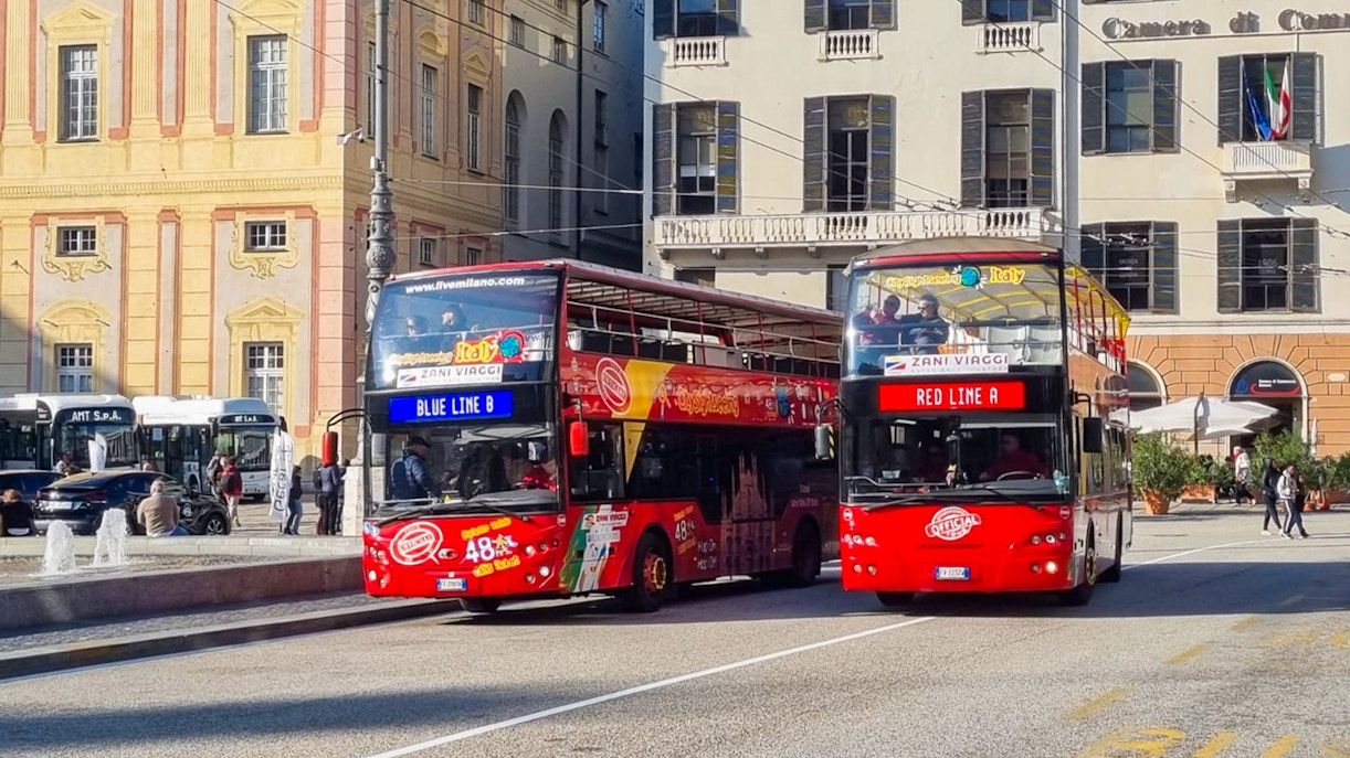 Genoa hop-on hop-off bus tour passing by historic city buildings.