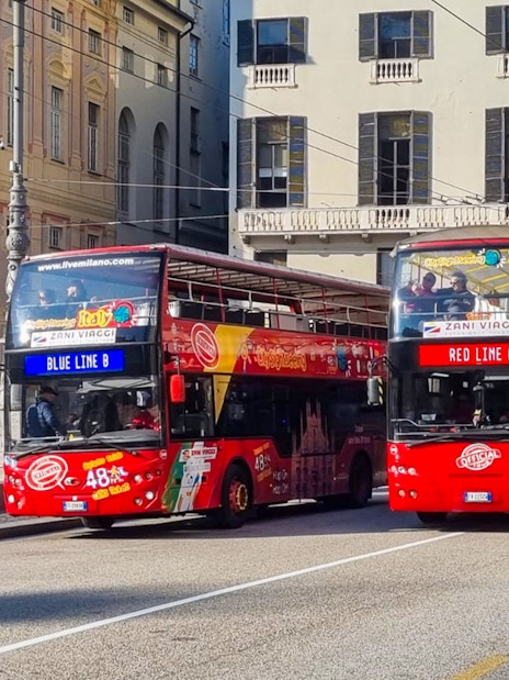 Hop-on hop-off tour buses in Genoa city center.