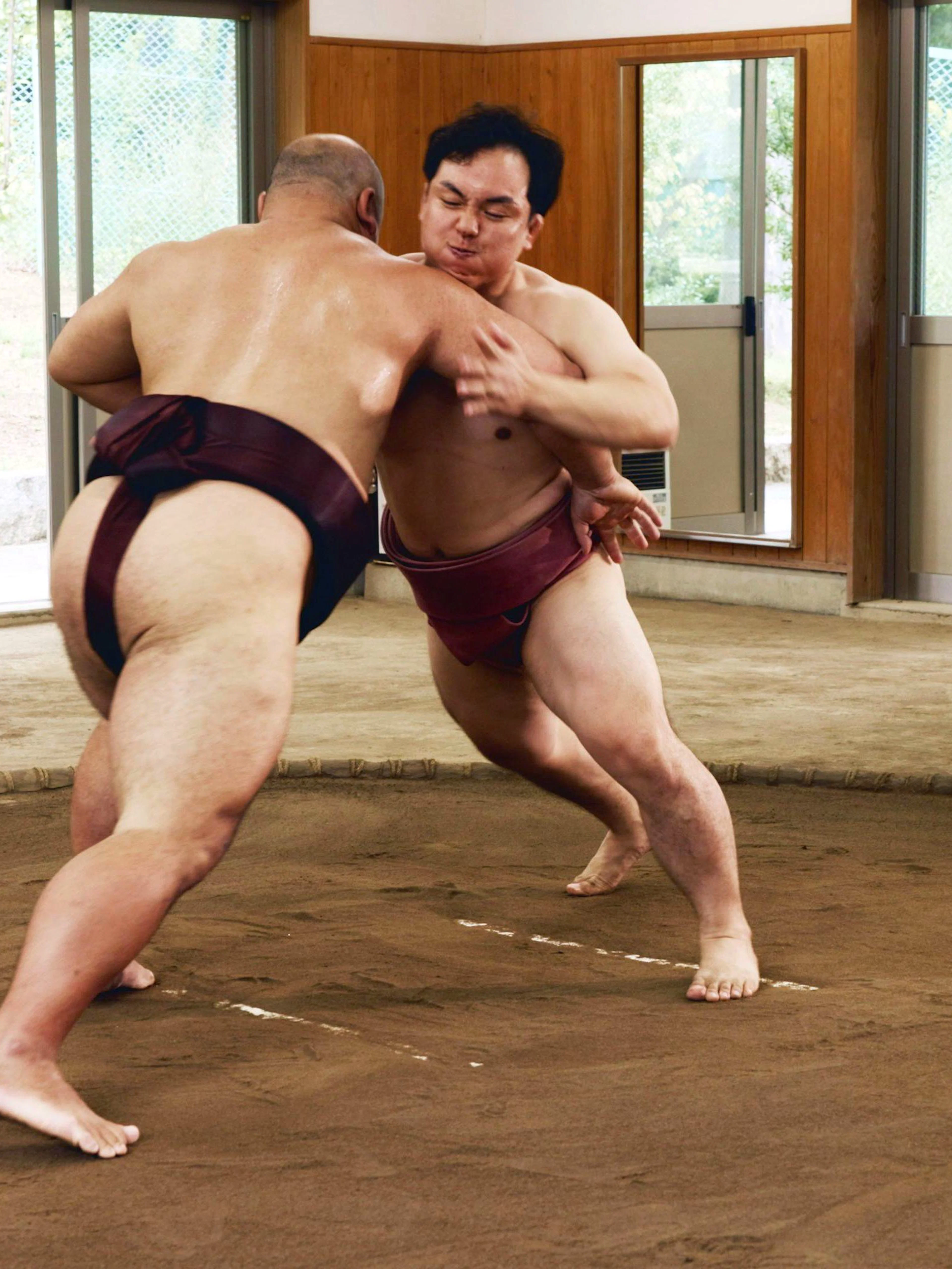 Sumo wrestlers grappling in a dohyo ring during a traditional match in Japan.