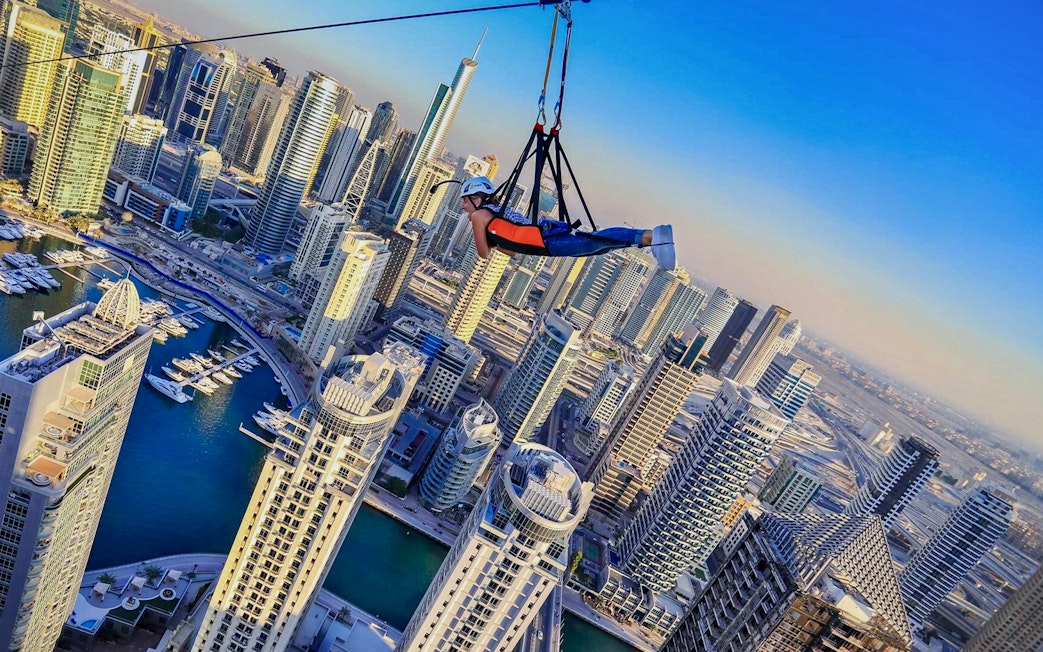 Person ziplining over Dubai Marina skyscrapers on XLine.