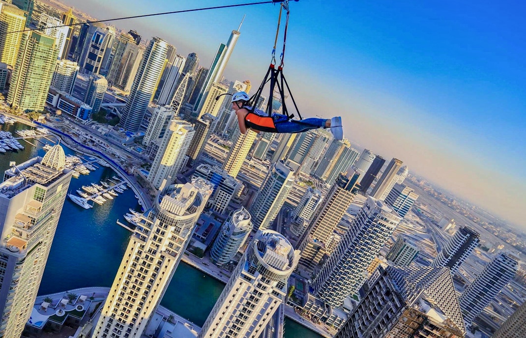 Person ziplining over Dubai Marina skyscrapers on XLine.