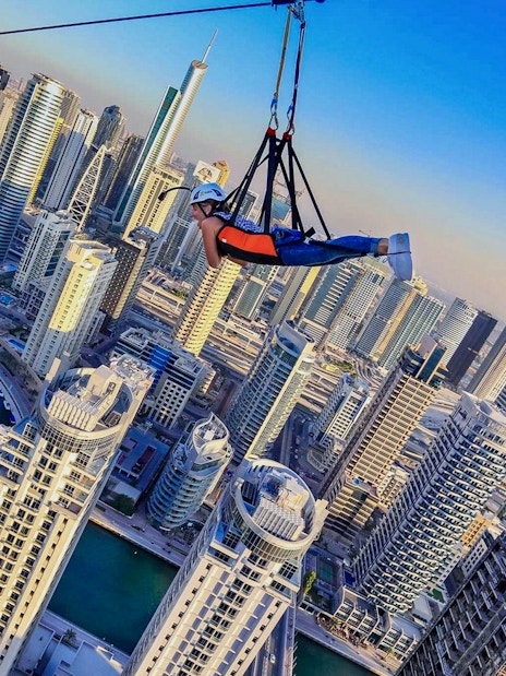 Person ziplining over Dubai Marina skyscrapers on XLine.