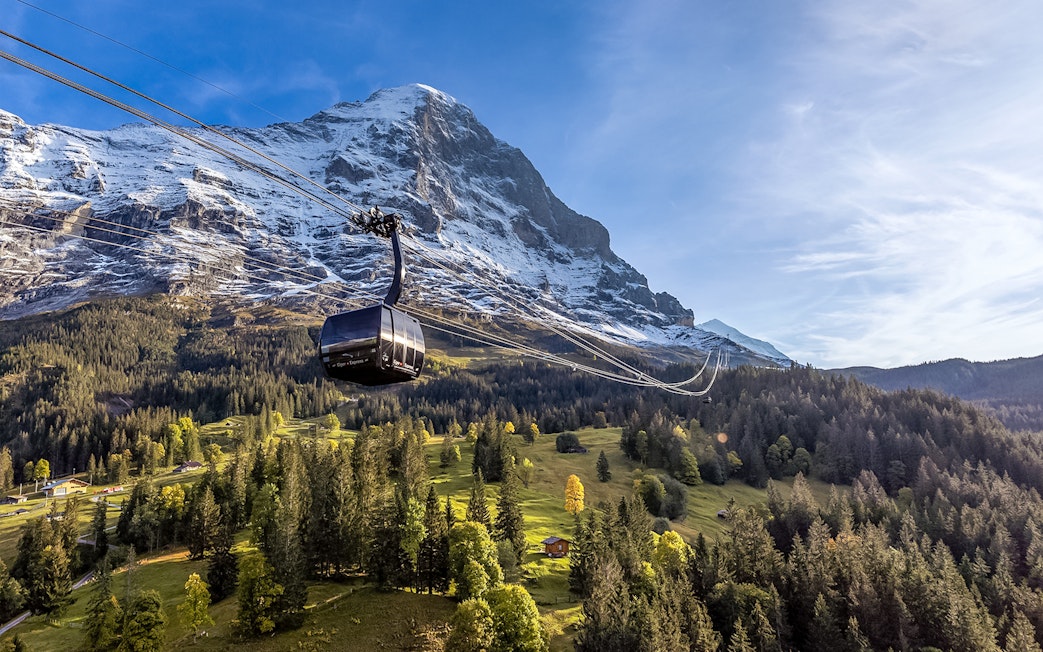 Cable car ascending to Jungfraujoch with snow-capped mountain backdrop, Switzerland.