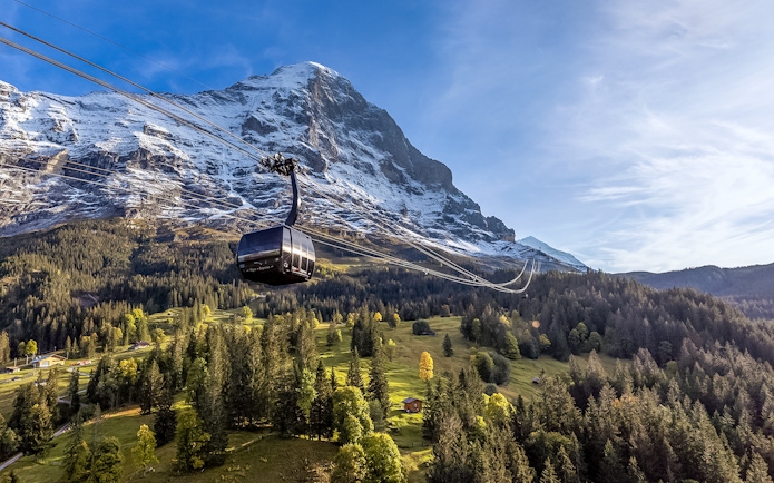 Cable car ascending to Jungfraujoch with snow-capped mountain backdrop, Switzerland.