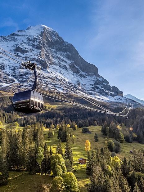 Cable car ascending to Jungfraujoch with snow-capped mountain backdrop, Switzerland.