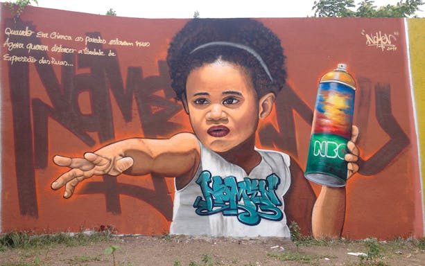 Street art mural of a child holding a spray can in Lisbon.