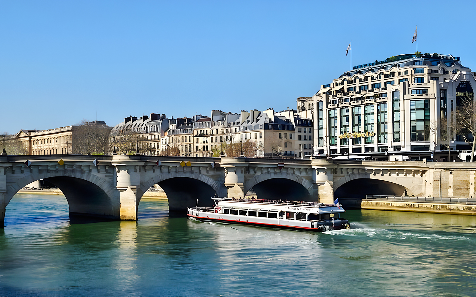Seine River cruise boat passing under a bridge in Paris, France.