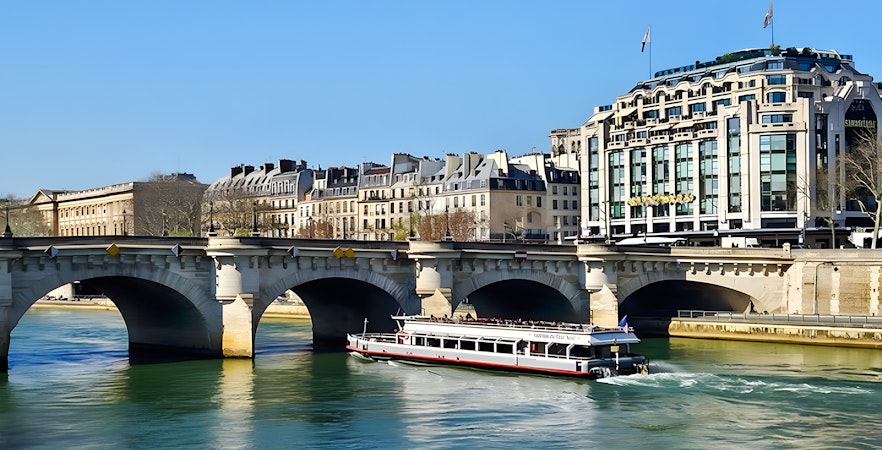Seine River cruise boat passing under a bridge in Paris, France.