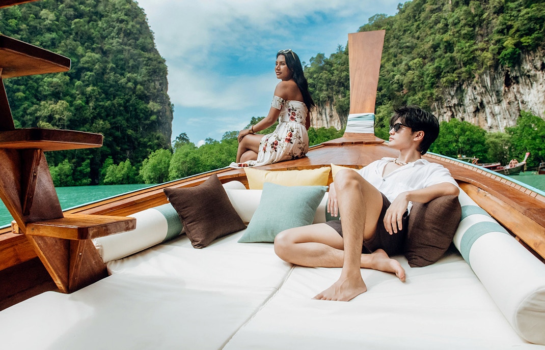 Longtail boat sailing in Krabi with limestone cliffs and lush greenery in the background.