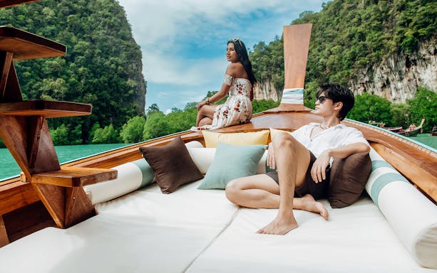 Longtail boat sailing in Krabi with limestone cliffs and lush greenery in the background.