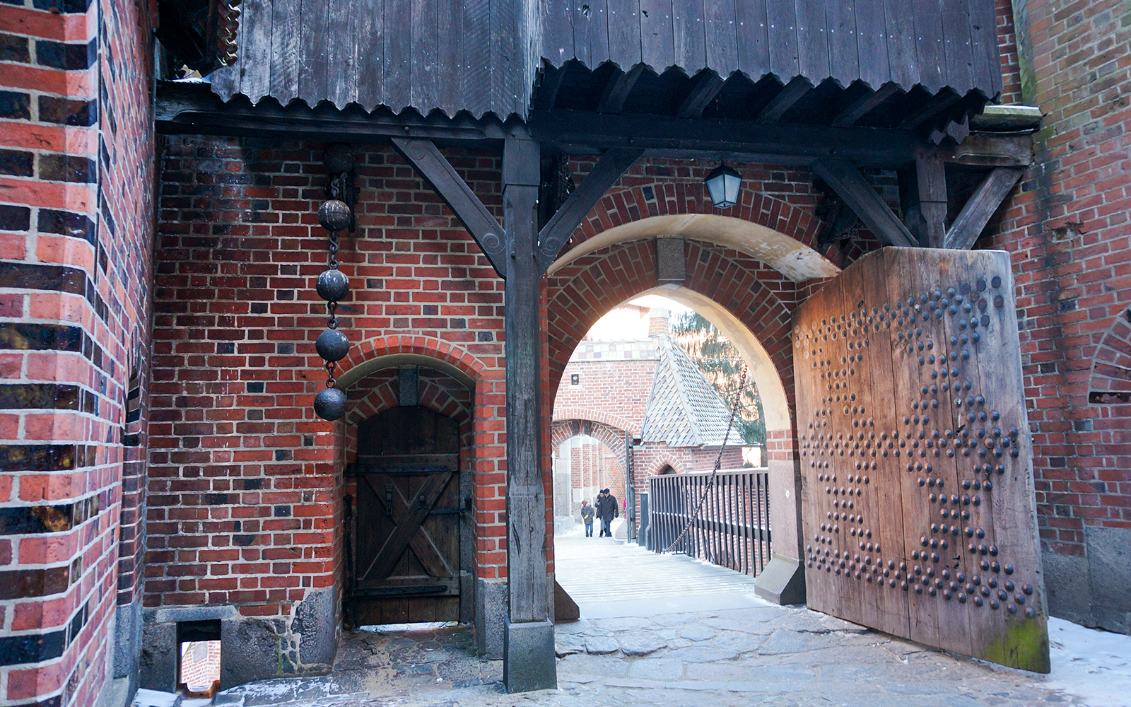 Malbork Castle entrance with wooden gate and brick archway, Poland.