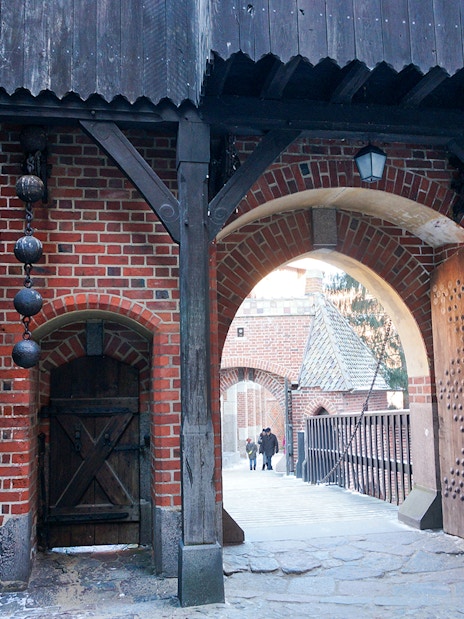 Malbork Castle entrance with wooden gate and brick archway, Poland.