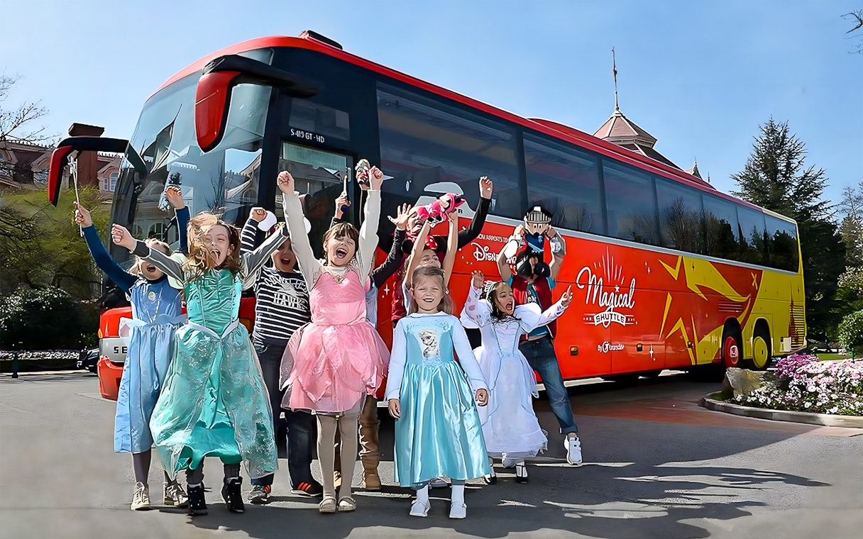Young girls in costumes celebrating near the Magical Shuttle at Disneyland Paris.
