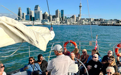 Guests enjoying a 3-course dinner cruise with drinks on Auckland Harbour, city skyline in background.