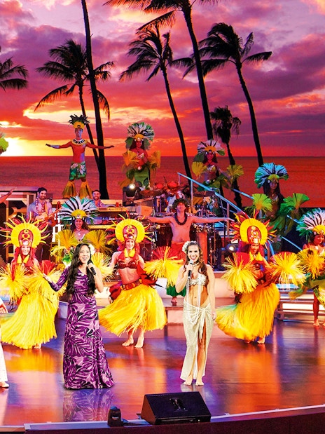 Performers in traditional Hawaiian attire on stage at RockAHula Show, Honolulu.