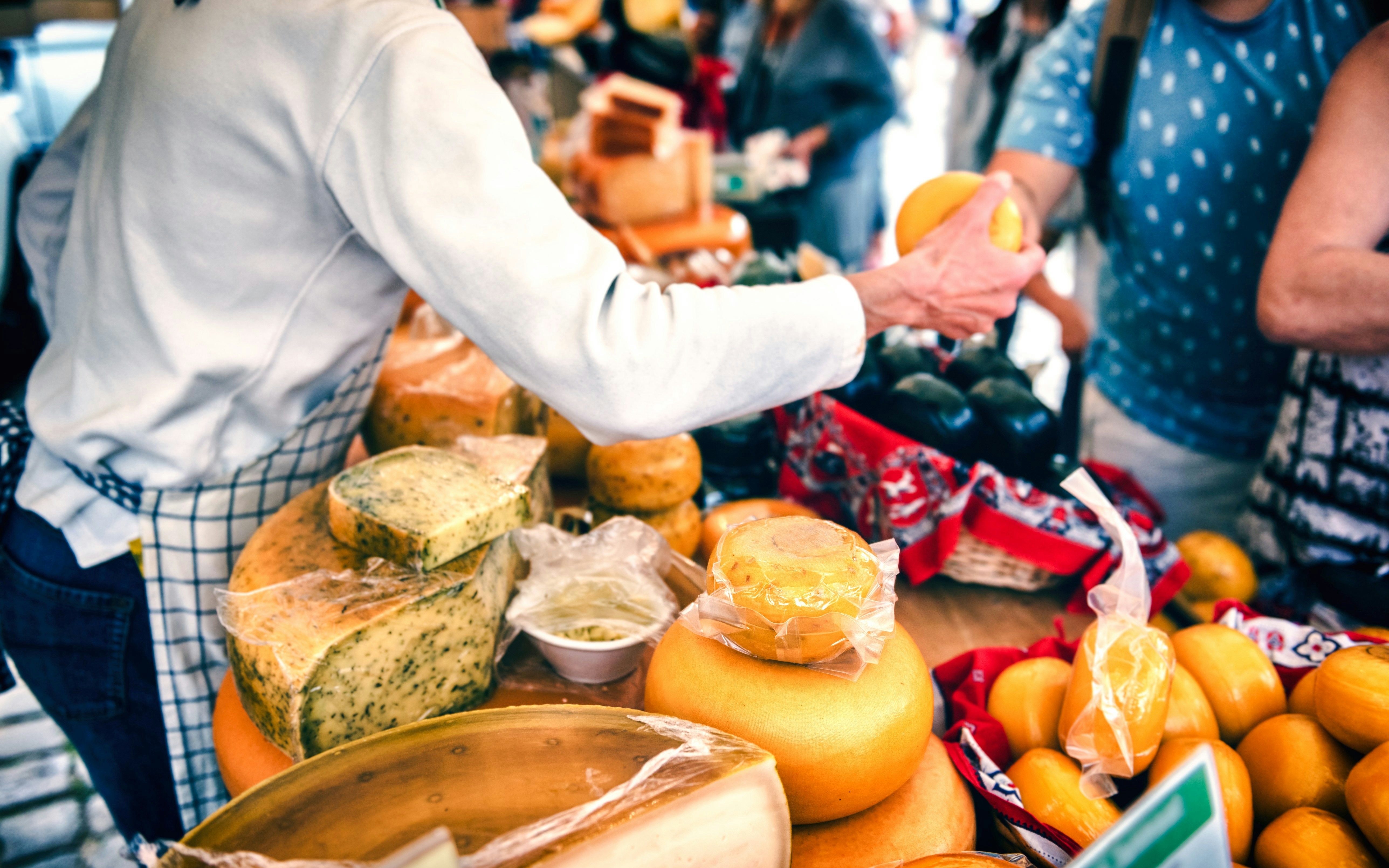 Cheese selection at Keukenhof farm shop with customer interaction.