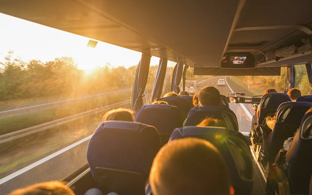 Passengers on a bus traveling to tandem skydiving in Cairns at sunset.