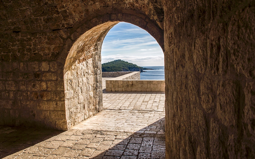 Archway view from Lovrijenac Fort overlooking Adriatic Sea and distant hills.
