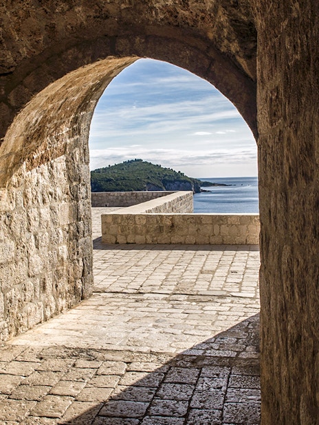 Archway view from Lovrijenac Fort overlooking Adriatic Sea and distant hills.