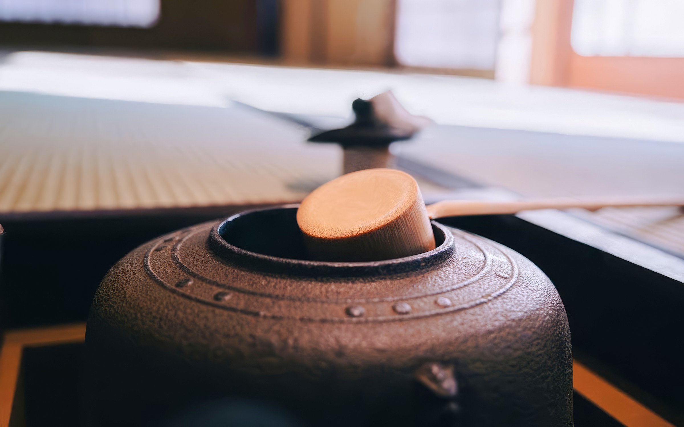 Ladle resting on a traditional Japanese tea kettle during a tea ceremony.