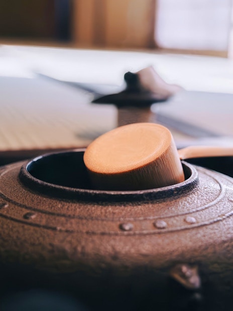 Ladle resting on a traditional Japanese tea kettle during a tea ceremony.