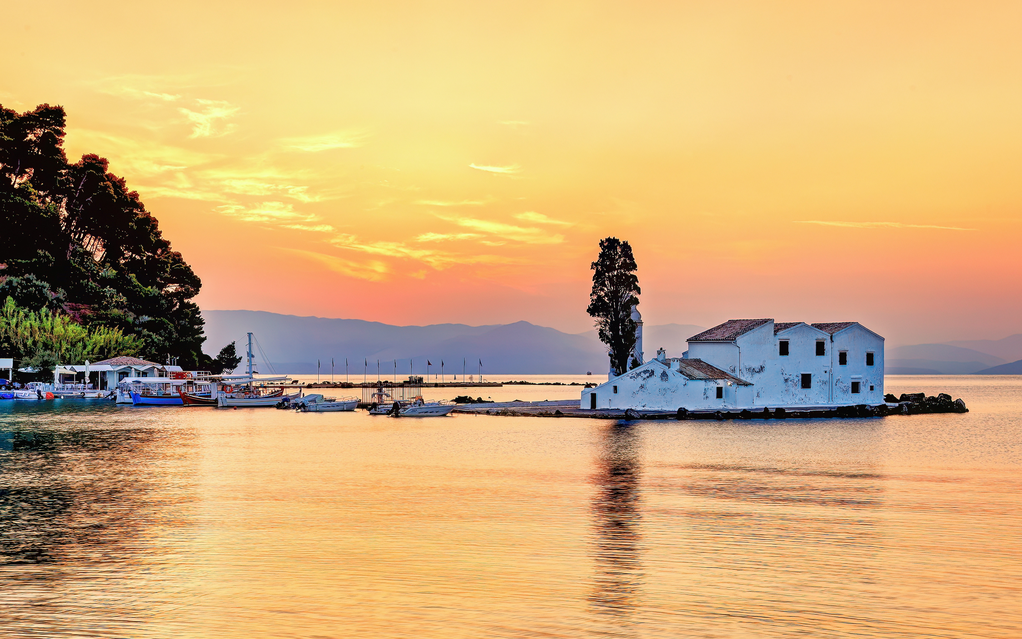 Sunset view of Panagia Vlacherna island with boats in Corfu, Greece.