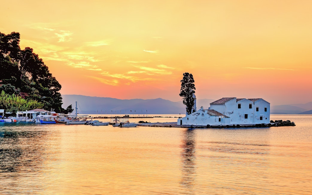 Sunset view of Panagia Vlacherna island with boats in Corfu, Greece.