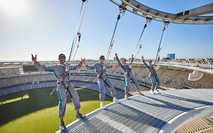 Visitors harnessed on Optus Stadium roof during Vertigo experience in Perth, Australia.