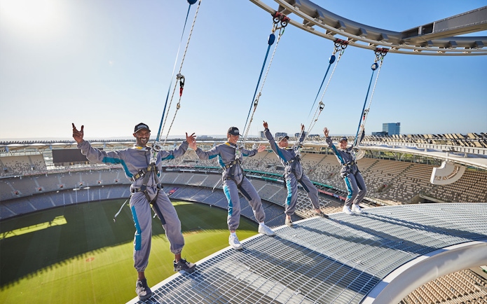 Visitors harnessed on Optus Stadium roof during Vertigo experience in Perth, Australia.